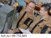 engineer recording precision measurement with his assistant. Стоковое фото, агентство Ingram Publishing / Фотобанк Лори