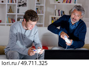 Father and adolescent son playing computer game. Стоковое фото, агентство Ingram Publishing / Фотобанк Лори