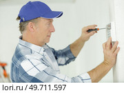 man screwing a device on the wall. Стоковое фото, агентство Ingram Publishing / Фотобанк Лори