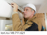 man worker adjusting blinds molding. Стоковое фото, агентство Ingram Publishing / Фотобанк Лори