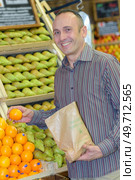 Man choosing clementines in greengrocers. Стоковое фото, агентство Ingram Publishing / Фотобанк Лори