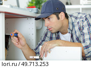 man attaching pipe under sink. Стоковое фото, агентство Ingram Publishing / Фотобанк Лори