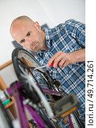 man fixing bicycle in garage. Стоковое фото, агентство Ingram Publishing / Фотобанк Лори