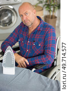 disabled man on wheelchair ironing clothing. Стоковое фото, агентство Ingram Publishing / Фотобанк Лори