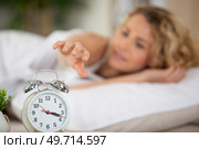 asleep girl stopping alarm clock on the bed. Стоковое фото, агентство Ingram Publishing / Фотобанк Лори