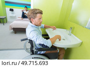 man on wheelchair washing hands in bathroom. Стоковое фото, агентство Ingram Publishing / Фотобанк Лори