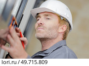 man measuring window prior to installation. Стоковое фото, агентство Ingram Publishing / Фотобанк Лори
