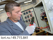 an electrician using cable strippers. Стоковое фото, агентство Ingram Publishing / Фотобанк Лори