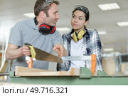 a man and woman using a handsaw. Стоковое фото, агентство Ingram Publishing / Фотобанк Лори