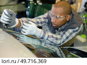 portrait of mechanic positioning windscreen. Стоковое фото, агентство Ingram Publishing / Фотобанк Лори