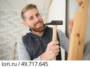 a handsome construction man using a hammer to nail wood. Стоковое фото, агентство Ingram Publishing / Фотобанк Лори