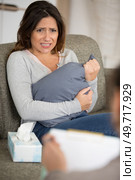 stressed woman hugging a pillow while feeling anxious at psychologist. Стоковое фото, агентство Ingram Publishing / Фотобанк Лори
