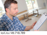 Carpenter looking at his clipboard. Стоковое фото, агентство Ingram Publishing / Фотобанк Лори