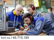 senior engineer instructing apprentices at machine bench. Стоковое фото, агентство Ingram Publishing / Фотобанк Лори