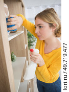 young woman dusting a bookshelf. Стоковое фото, агентство Ingram Publishing / Фотобанк Лори