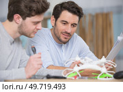 two men following instructions to assemble a drone. Стоковое фото, агентство Ingram Publishing / Фотобанк Лори
