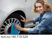 smiling woman use sponge to wipe black tire. Стоковое фото, агентство Ingram Publishing / Фотобанк Лори