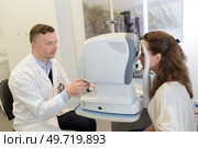 woman looking at eye test machine in ophthalmologist. Стоковое фото, агентство Ingram Publishing / Фотобанк Лори