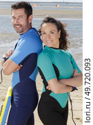 portrait of couple on beach wearing wetsuits. Стоковое фото, агентство Ingram Publishing / Фотобанк Лори