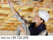 female electrician feeding cable through roof joists. Стоковое фото, агентство Ingram Publishing / Фотобанк Лори