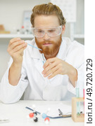 lab assistant in outfit holding a flask and pipette. Стоковое фото, агентство Ingram Publishing / Фотобанк Лори