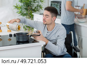disabled young man in wheelchair cooking a meal in kitchen. Стоковое фото, агентство Ingram Publishing / Фотобанк Лори