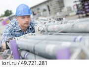 Worker pushing stack of scaffolding tubes. Стоковое фото, агентство Ingram Publishing / Фотобанк Лори