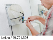 Man fitting hand drier in bathroom. Стоковое фото, агентство Ingram Publishing / Фотобанк Лори