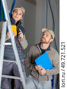 tradesman with female electrician on stepladder. Стоковое фото, агентство Ingram Publishing / Фотобанк Лори