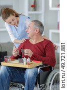 young beautiful nurse helpping disabled elder man at home. Стоковое фото, агентство Ingram Publishing / Фотобанк Лори