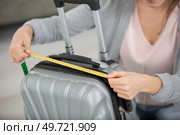woman inspecting hand luggage measurement using measuring tape. Стоковое фото, агентство Ingram Publishing / Фотобанк Лори