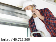 worker on the phone climbing to insulate house roof. Стоковое фото, агентство Ingram Publishing / Фотобанк Лори