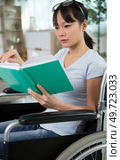 young woman in wheelchair holding book. Стоковое фото, агентство Ingram Publishing / Фотобанк Лори