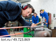 blacksmith holds metal with tongs and hammers on anvil. Стоковое фото, агентство Ingram Publishing / Фотобанк Лори