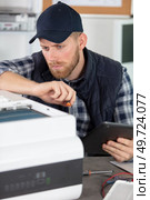 technician repairing printer and holding tablet. Стоковое фото, агентство Ingram Publishing / Фотобанк Лори
