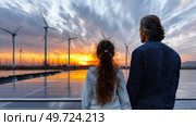 Father and daughter looking at solar panels. Solar farm and sunlight at sunset. Solar energy for green energy. Sustainable renewable energy. Photovoltaic power plant or solar park. Energy sustainability. Стоковое AI-изображение, AI-художник ALLA YURTAYEVA / Фотобанк Лори