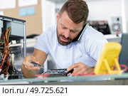 computer repairman specialist on the phone repairing computer desktop. Стоковое фото, агентство Ingram Publishing / Фотобанк Лори