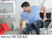 disabled man trying to sit on a couch. Стоковое фото, агентство Ingram Publishing / Фотобанк Лори