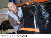 elder worker using shrink wrap to pack items in warehouse. Стоковое фото, агентство Ingram Publishing / Фотобанк Лори