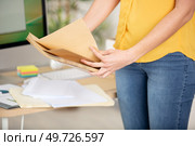 freelancer opening a padded envelope in an office or home. Стоковое фото, агентство Ingram Publishing / Фотобанк Лори