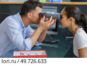women looking at eye test machine in ophthalmology clinic. Стоковое фото, агентство Ingram Publishing / Фотобанк Лори
