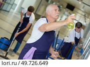 male cleaning team at work senior operative spraying product. Стоковое фото, агентство Ingram Publishing / Фотобанк Лори