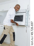 Man fitting oven into kitchen. Стоковое фото, агентство Ingram Publishing / Фотобанк Лори