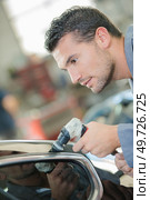 Mechanic buffing roof of car with machine. Стоковое фото, агентство Ingram Publishing / Фотобанк Лори