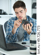 young male technician working on dismantled camera lens. Стоковое фото, агентство Ingram Publishing / Фотобанк Лори