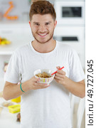 good looking young man eating cereal and smiling in kitchen. Стоковое фото, агентство Ingram Publishing / Фотобанк Лори