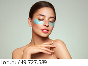 A young beautiful smiling woman with cosmetic patches on her eyes. Cosmetic procedures skin care around the eyes. Perfect healthy facial skin. Стоковое фото, агентство Ingram Publishing / Фотобанк Лори