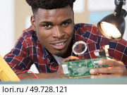 electronics repair master using a magnifying glass. Стоковое фото, агентство Ingram Publishing / Фотобанк Лори