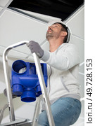 man on stepladder installing a ventilation system. Стоковое фото, агентство Ingram Publishing / Фотобанк Лори