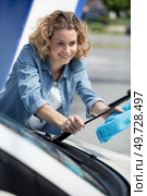 cheerful woman changes windshield wiper on her car. Стоковое фото, агентство Ingram Publishing / Фотобанк Лори